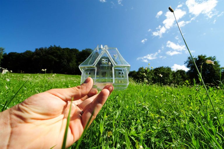 Gläsernes Miniaturhaus auf einer Wiese