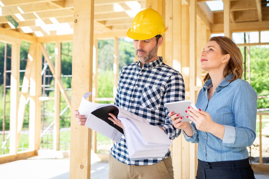 Architekt mit Plänen trifft sich mit Eigentümer des Gebäudes auf der Baustelle.